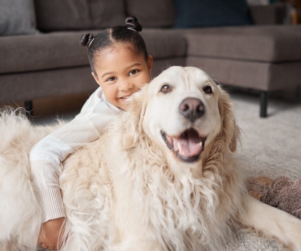 Young child holds her autism support dog while smiling at the camera.