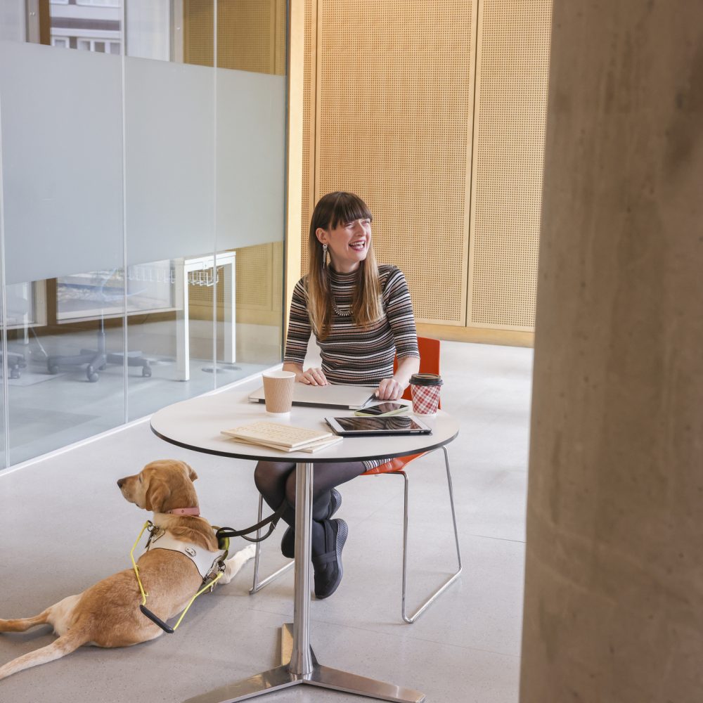 Smiling blind woman sitting in modern office with guide dog
