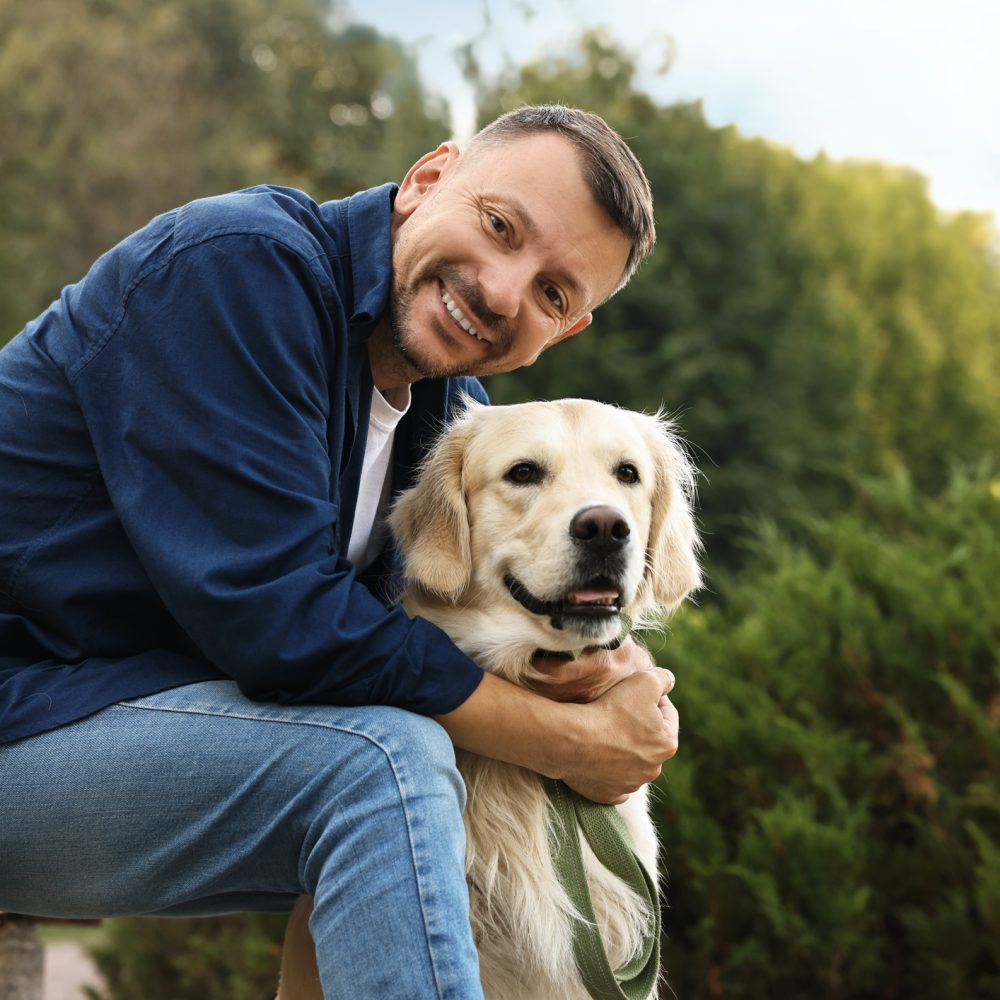 Smiling man with cute Golden Retriever dog on spring day